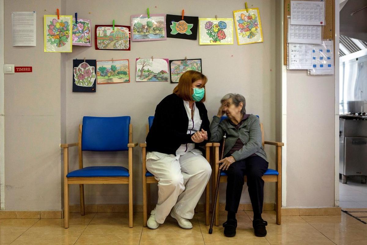 FOTOGALERIA (3 de 15) GRAFCAT4555. PALLEJÀ (BARCELONA), 11/04/2020.- Una asistente conversa con una anciana en la residencia geriátrica Roma de Pallejà (Barcelona), un centro en el que no se ha registrado ningún caso positivo de coronavirus. Al comienzo de la crisis sanitaria los responsables del centro tomaron medidas excepcionales como limitación de visitas, desinfección constante, máquinas purificadoras de aire y control de temperatura a los residentes varas veces al día, y hasta el momento han conseguido mantener a sus usuarios libres de contagio, a pesar de ser un colectivo especialmente castigado por la enfermedad. EFE/Enric Fontcuberta