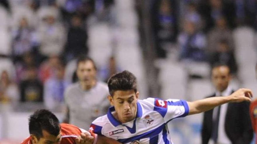 Pizzi pugna por el balón ante Medel durante el partido contra el Sevilla en Riazor. / juan varela