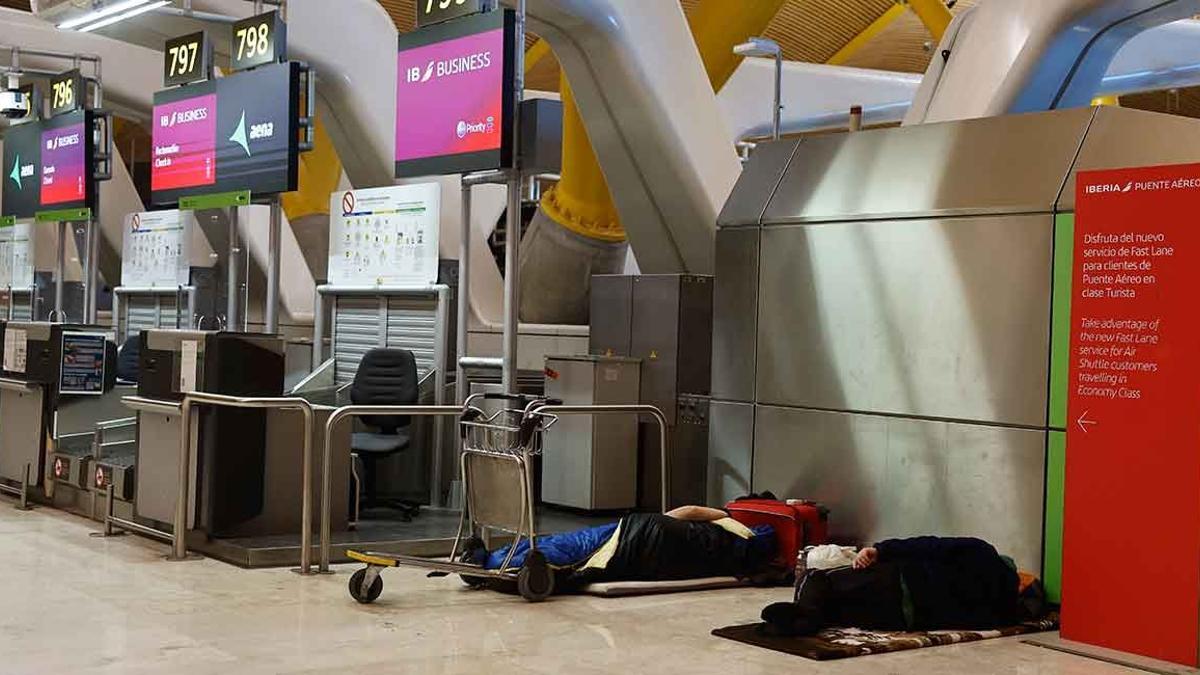 Dos personas durmiendo en el aeropuerto de Madrid.