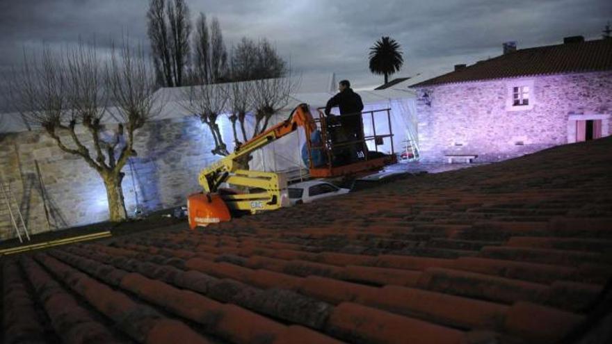 Varios operarios ultiman los preparativos de la boda, ayer, en el pazo de Drozo, y una señal, frente al hotel Finisterre. / carlos pardellas / fran martínez