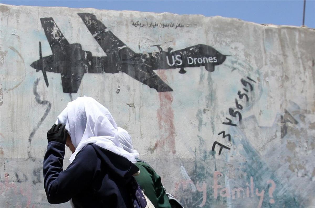 Una mujer camina frente a un muro con un grafiti que protesta contra los ataques aéreos con drones realizados por Estados Unidos en Sana,  Yemen.