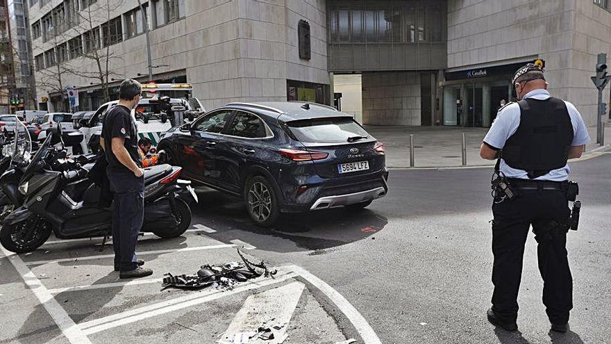 Un policia amb el cotxe implicat i restes del xoc a terra.