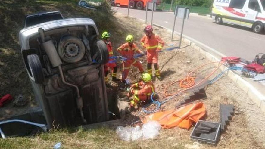 El turismo encajado en la acequia tras el rescate.