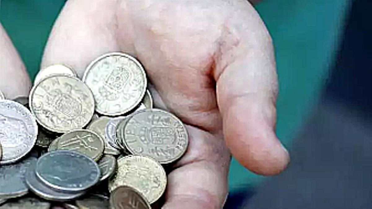 Monedas de 100 pesetas en las manos.