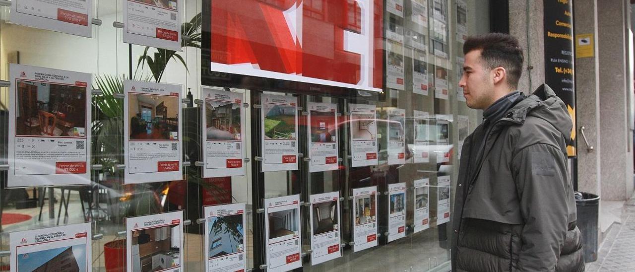 Un joven observa el escaparate de una inmobiliaria en Ourense