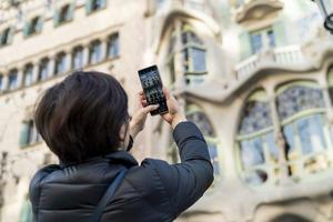 Archivo - Una turista realiza una fotografía con su teléfono móvil a la Casa Batlló de Barcelona