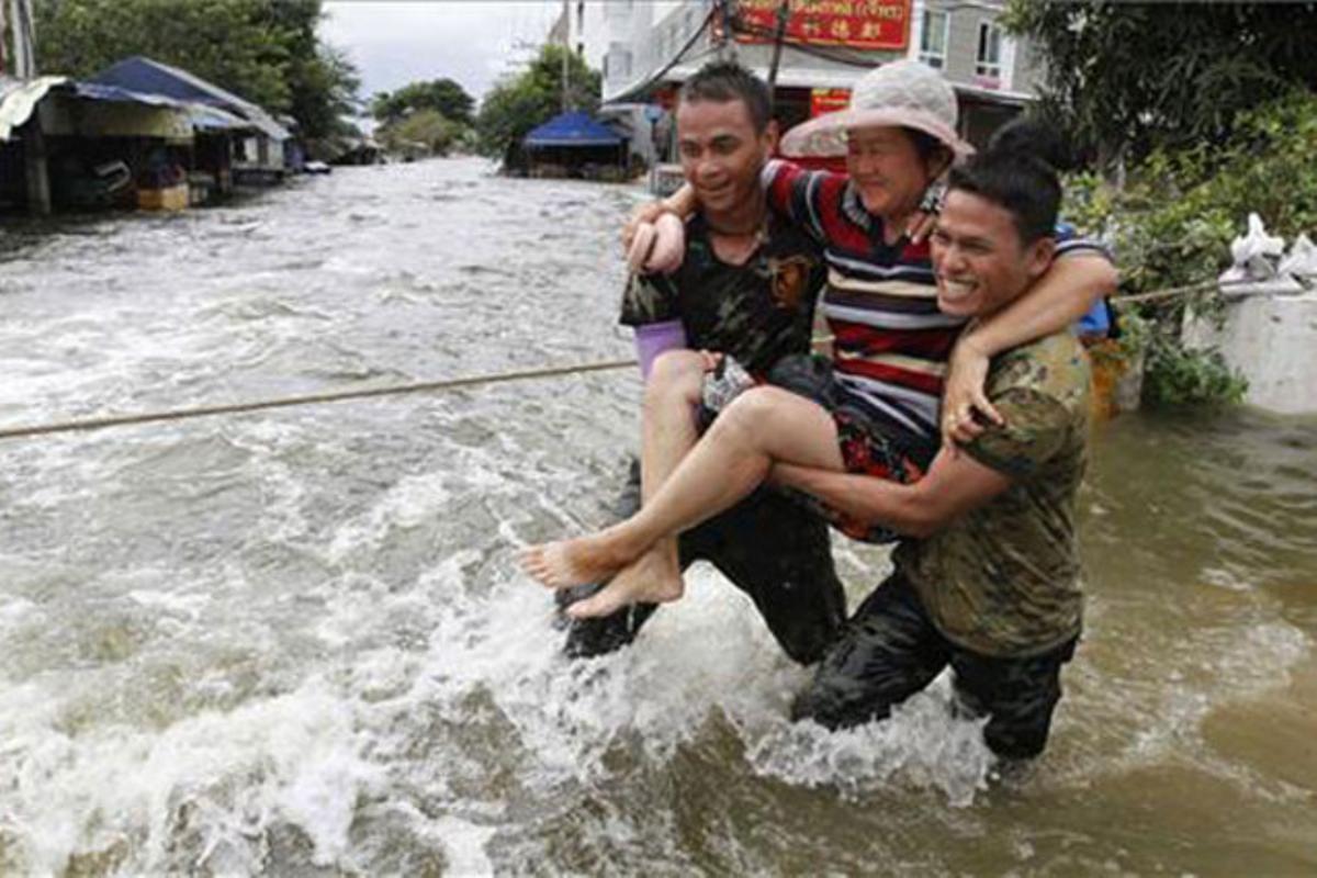 Dos soldats tailandesos porten a coll una dona en un carrer inundat a la província de Pathum Thani.