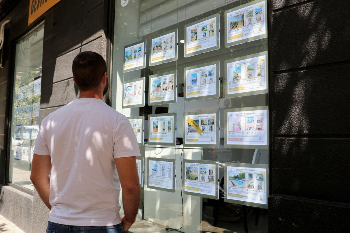 Un joven observa el escaparate de una inmobiliaria.