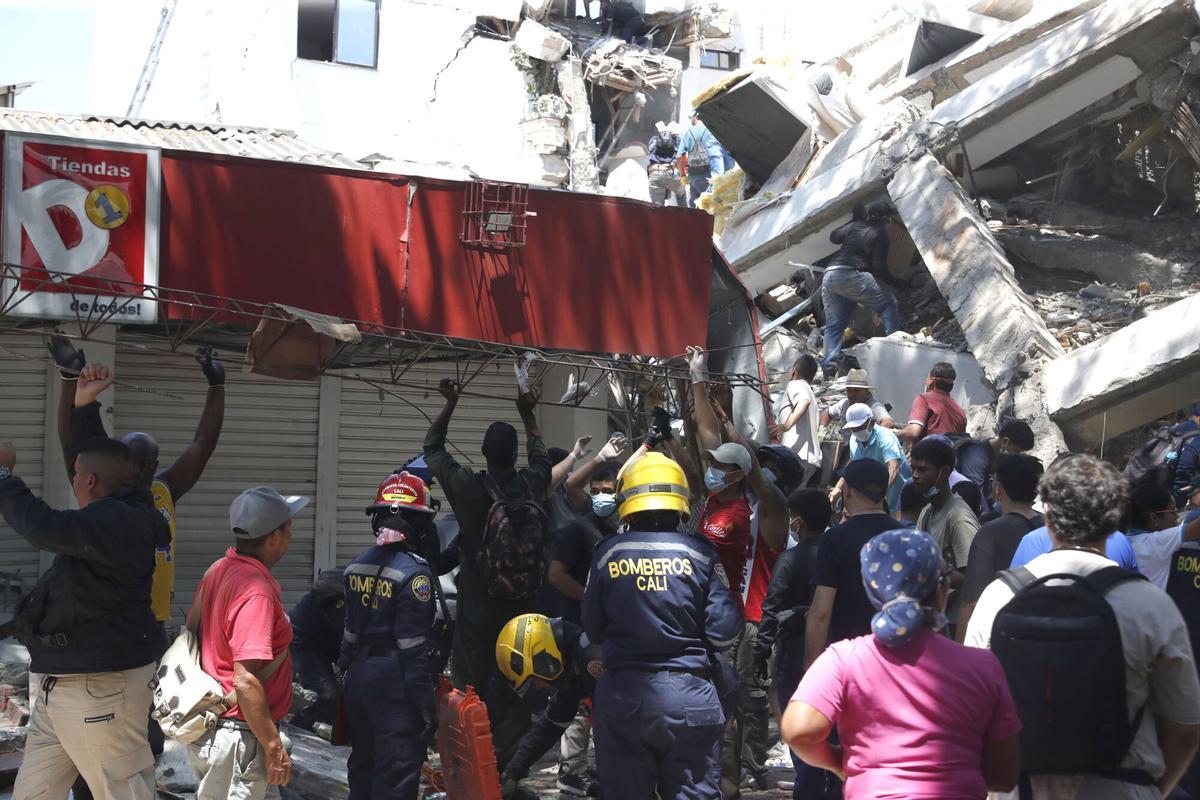 Integrantes del cuerpo de Bomberos de Cali y civiles buscan entre los escombros de edificaciones colapsadas por el terremoto de magnitud 7,4 que sacudió Colombia.