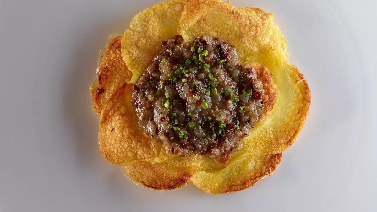 Las patatas Tinars, con 'botifarra del perol' y láminas crujientes del tubérculo.