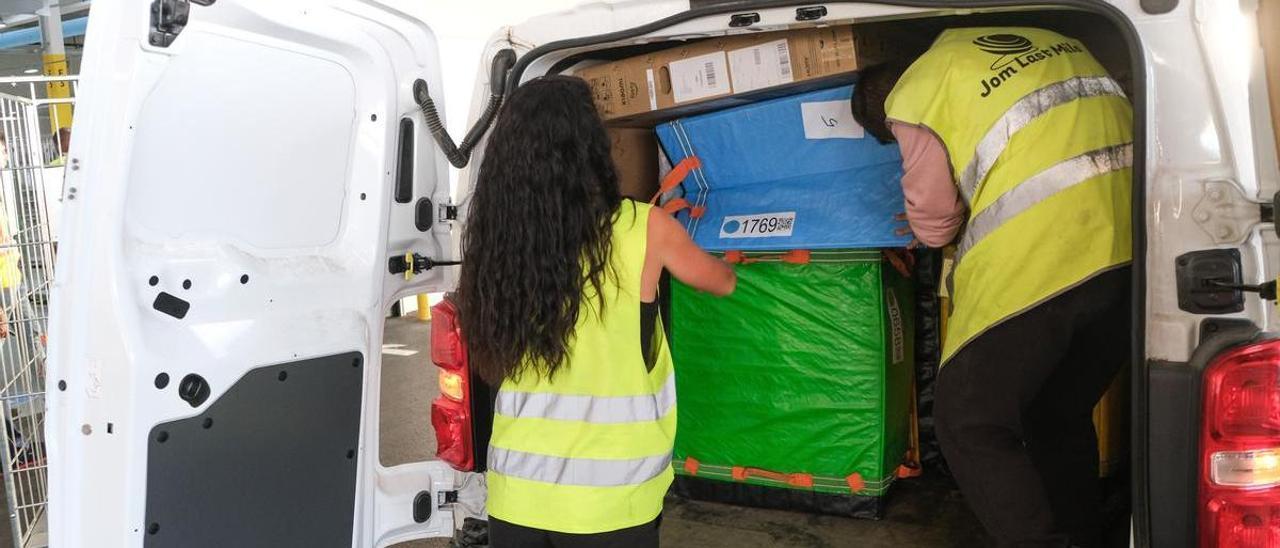 Dos trabajadores descargan paquetes de una furgoneta de reparto.