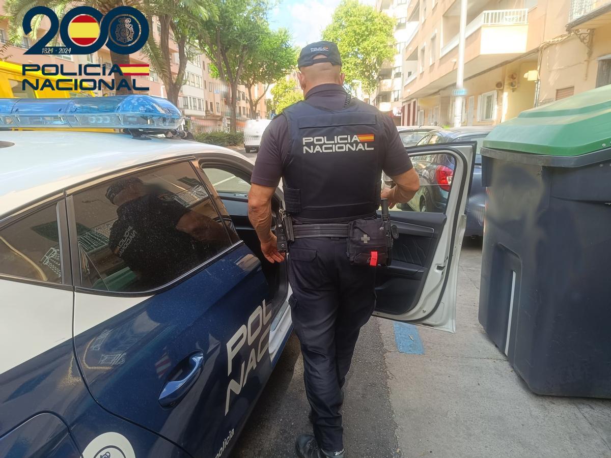 Un agente de la Policía Nacional junto a su coche patrulla.