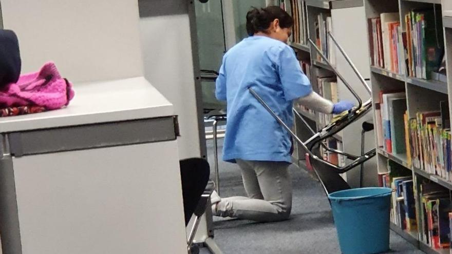 Una treballadora del servei de neteja desinfectant la biblioteca
