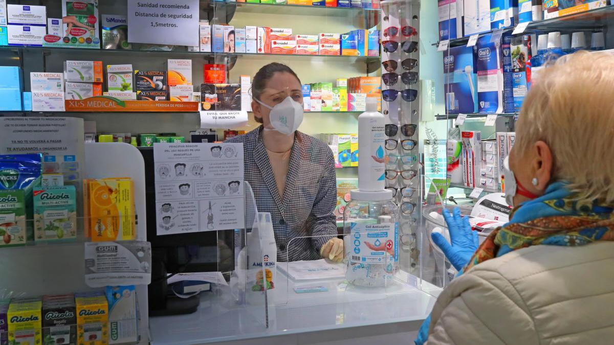 Una mujer recoge mascarillas en una farmacia de València durante el estado de alarma.