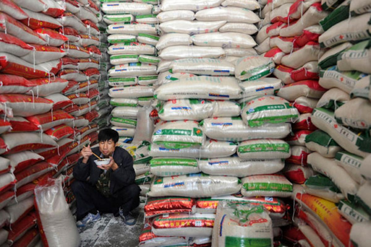 Un comerciant menja entre munts de sacs d’arròs en un mercat a Hefei, província d’Anhui (Xina).