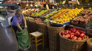 Una mujer haciendo la compra, ante un puesto de frutas y verduras en un mercado.