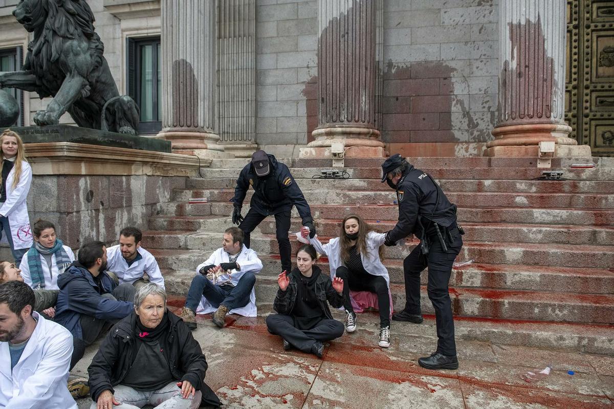 Protesta científica ante las puertas del Congreso de los Diputados en Madrid, el pasado 6 de abril, con la fachada manchada con agua color remolacha.