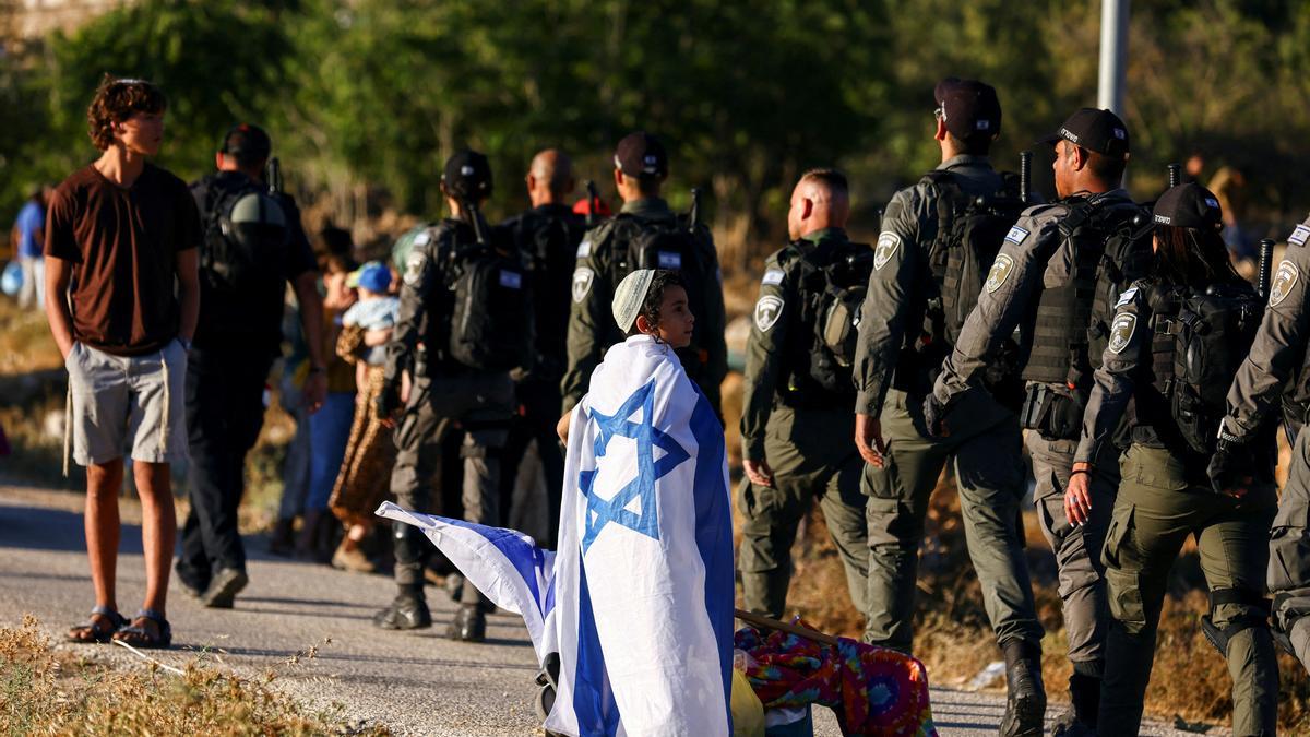 Un niño israelí junto a una patrulla de las fuerzas de seguridad del país, cerca del asentamiento de Kiryat Arba, en Hebrón (Cisjordania).