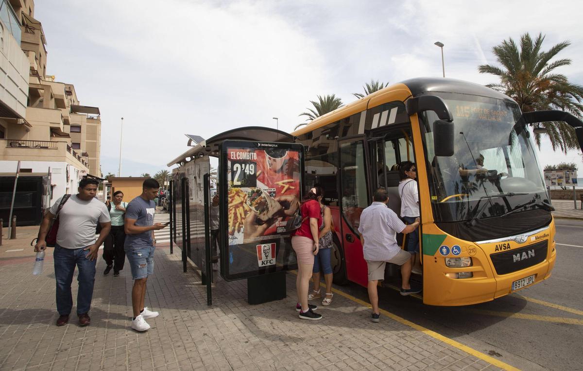 Varias personas al coger el autobús a València en el Port de Sagunt.