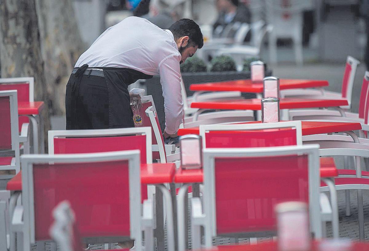 Un camarero limpia una silla en una terraza
