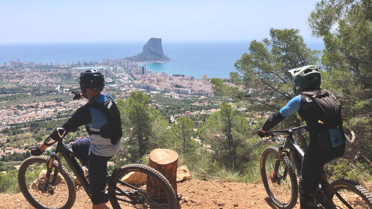 Dos ciclistas de montaña obsevan el pueblo de Calp desde la Serra d'Oltà