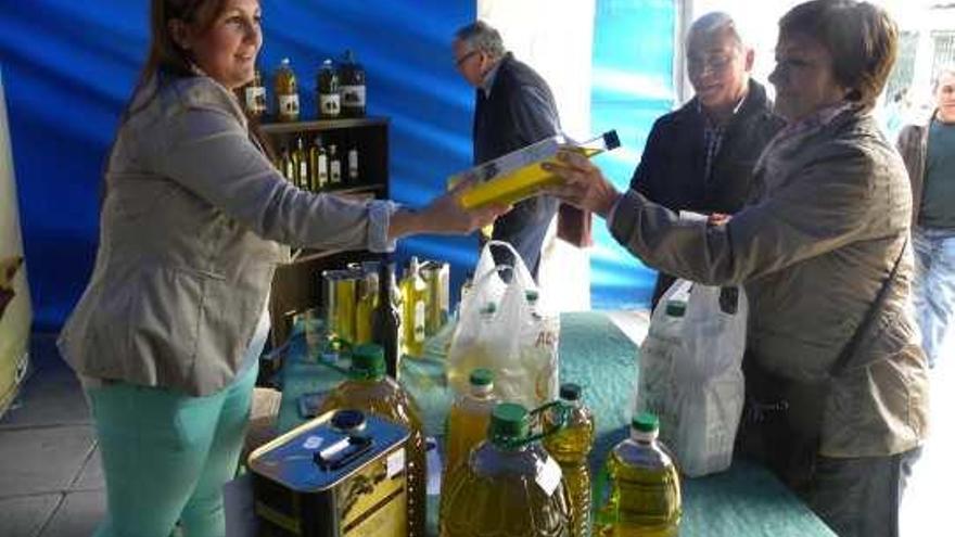 Un matrimonio procedente de Bilbao adquiere una botella de aceite de oliva en el expositor de la Cooperativa de San Isidro de Periana.