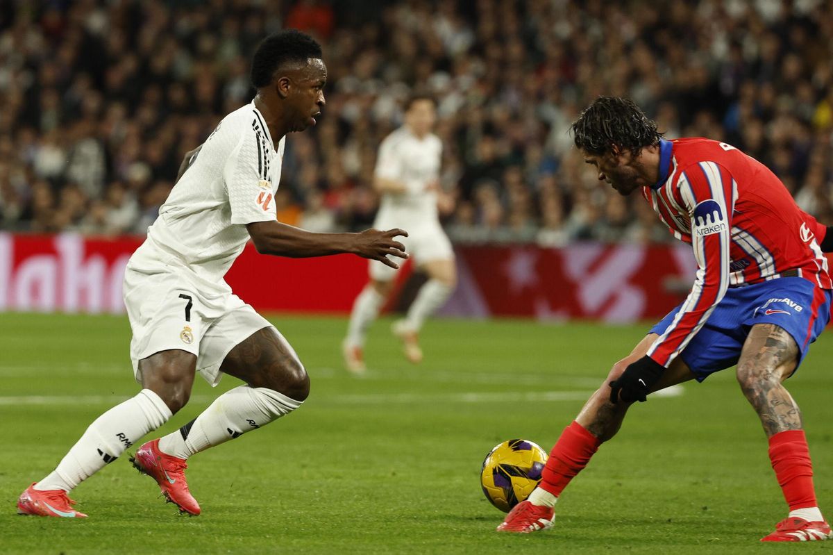 MADRID, 08/02/2025.- El delantero brasileño del Real Madrid, Vinicius Junior (i), intenta superar al centrocampista argentino del Atlético de Madrid, Rodrigo de Paul, durante el partido de LaLiga de fútbol que Real Madrid y Atlético de Madrid disputan este sábado en el estadio Santiago Bernabéu. EFE/Chema Moya.