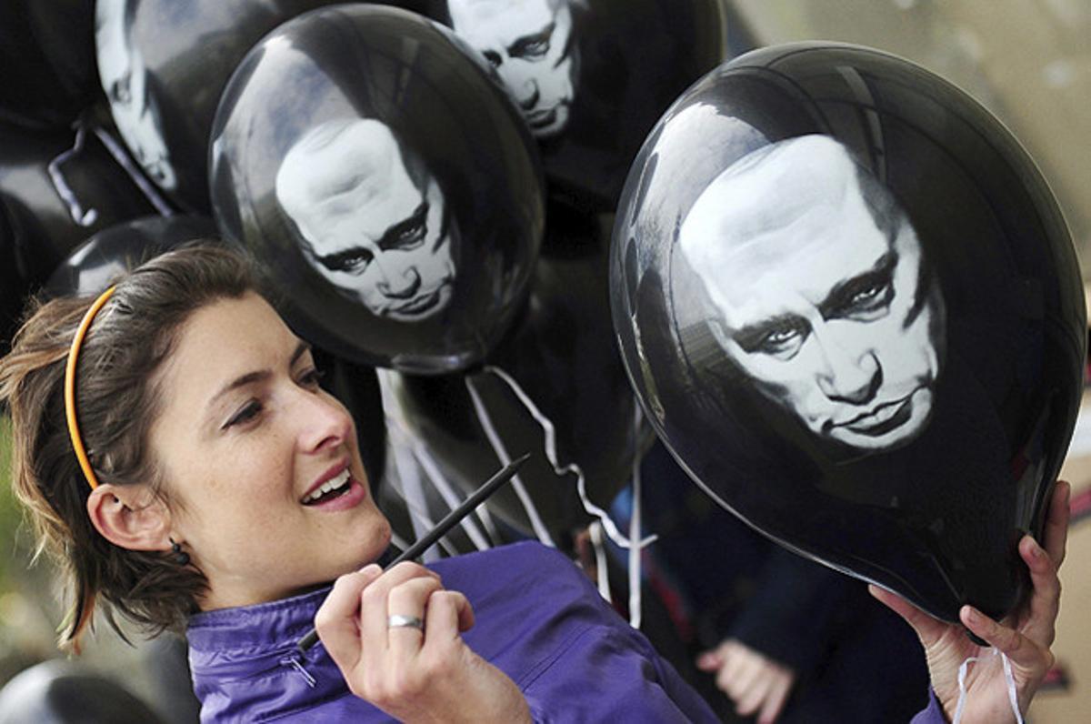 Una mujer pinta la imagen de Vladimir Putin en globo, durante una protesta organizada por Reporteros Sin Fronteras frente a la embajada rusa en Berlín.