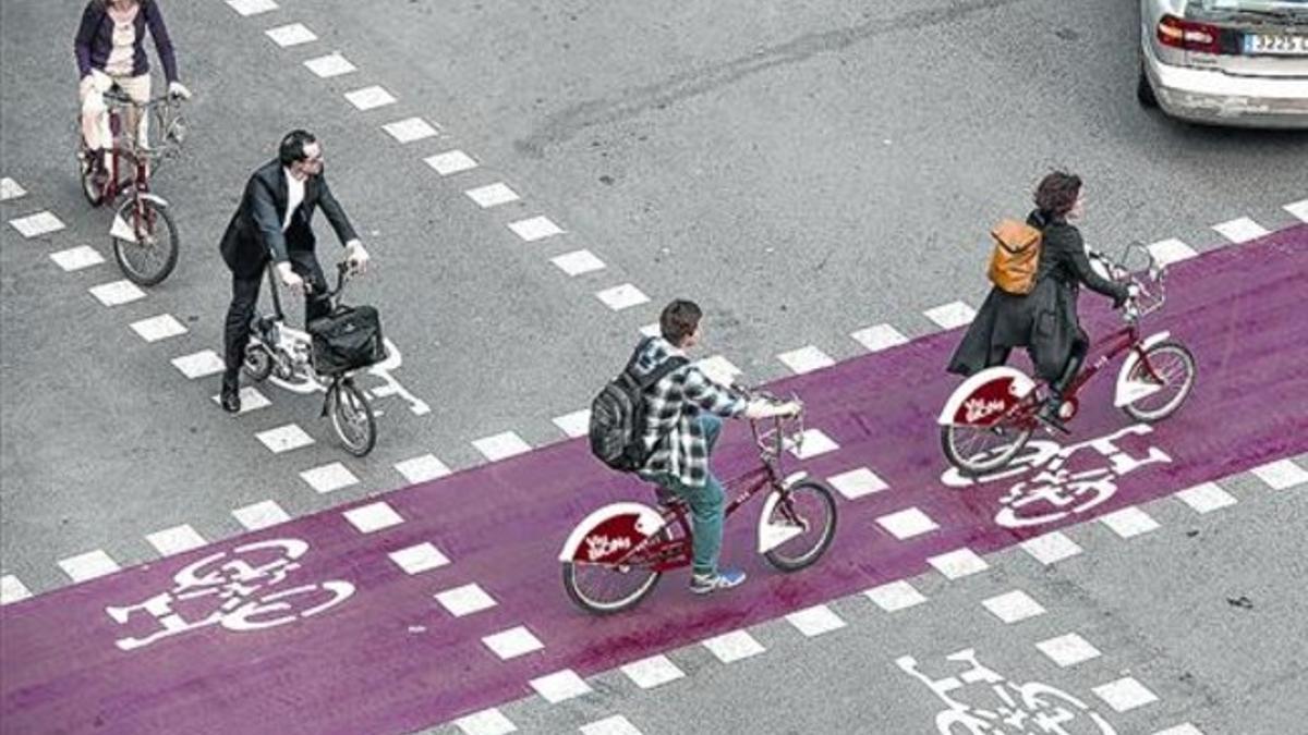 Varios ciclistas, en un cruce del Eixample provisto de carriles bici.