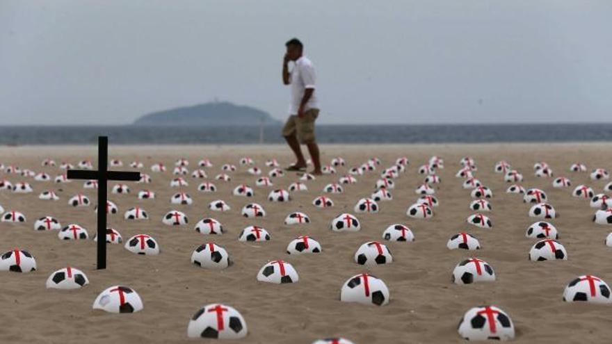 Una cruz entre balones semienterrados en la playa de Copacabana.