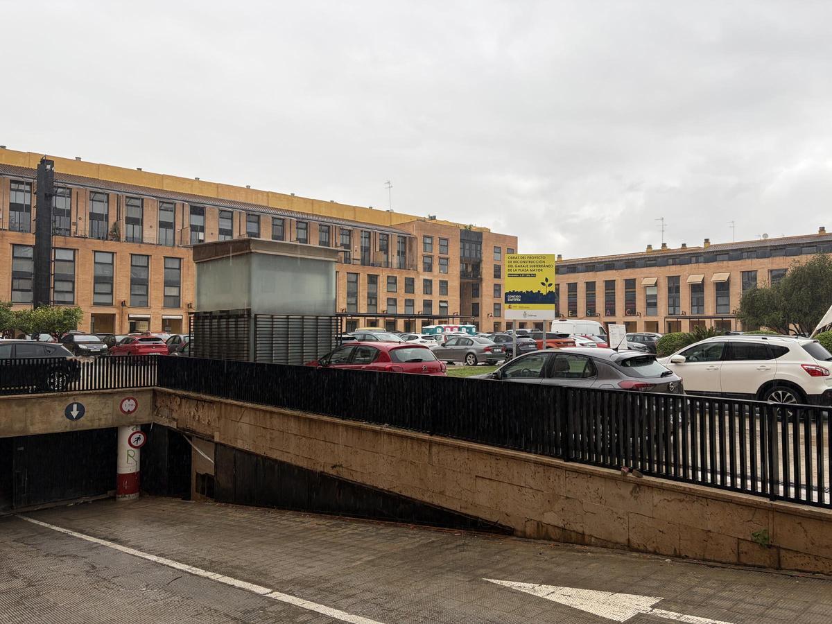 La entrada al aparcamiento y los coches estacionados en la plaza Mayor