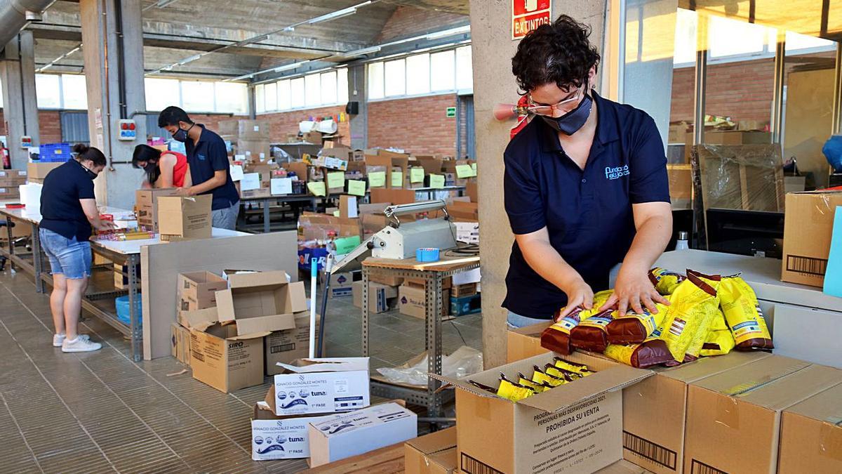 Usuaris del centre d’ocupació d’Els Joncs preparen els lots de menjar. | ACN