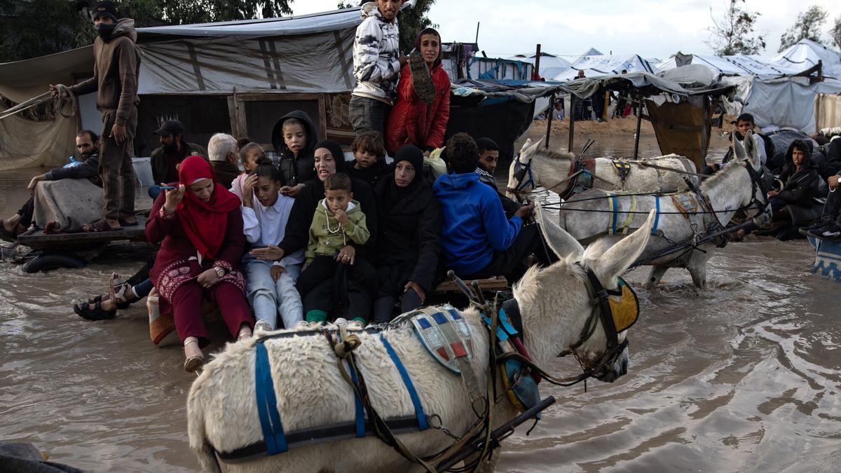 Palestinos se desplazan en carros tirados por animales por una calle inundada tras las fuertes lluvias en Gaza