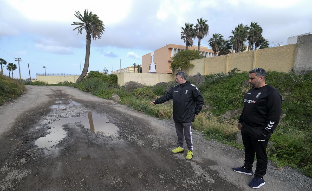 Miguel San Blas señala uno de los baches de la vía, con acumulación de agua tras las últimas lluvias. A su lado, Aythami, entrenador del Club de Fútbol de Lomo Blanco.