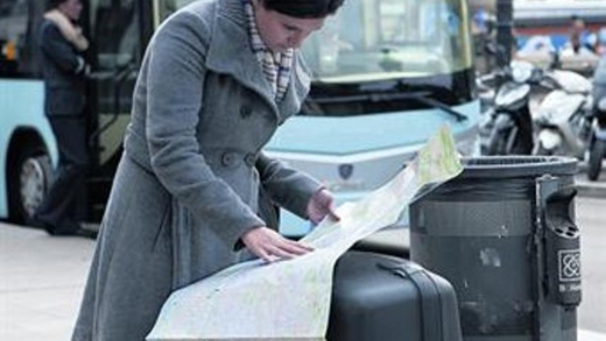 Una turista mira un plano ante la parada del Aerobús en plaza de Catalunya, ayer.