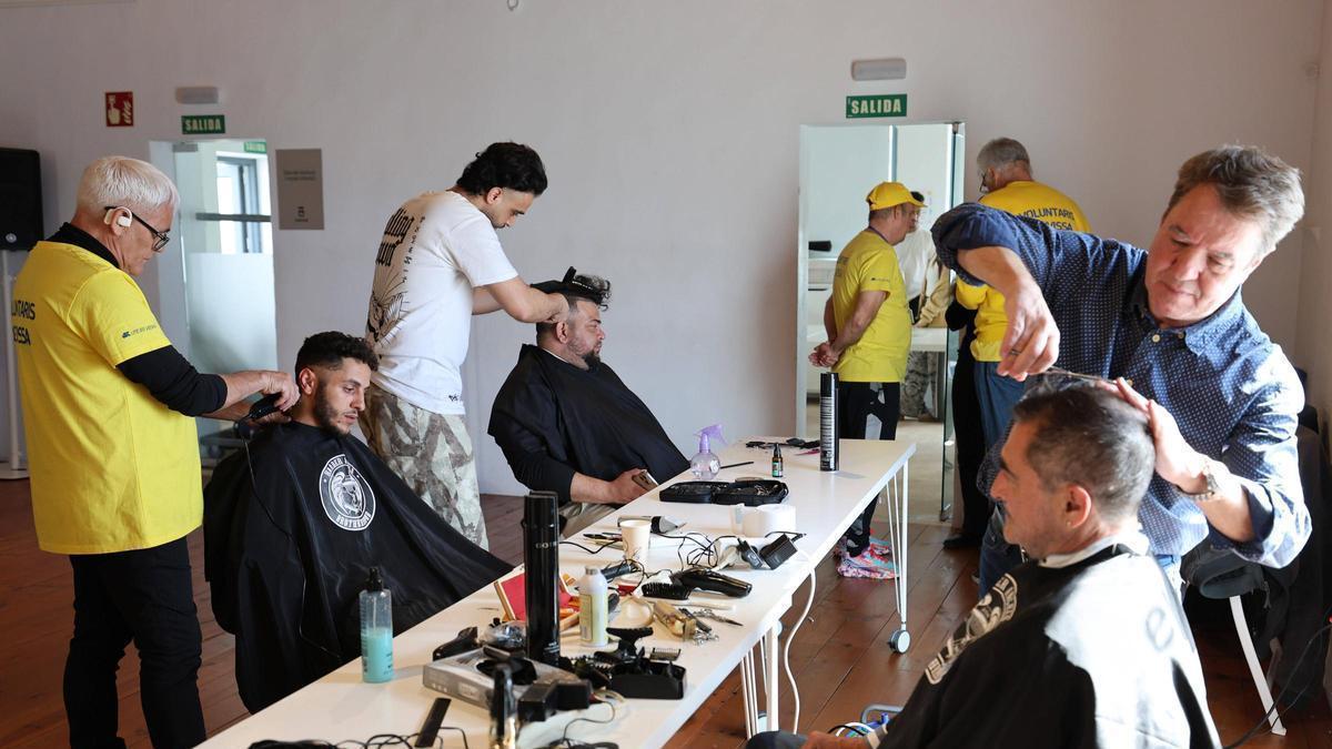 Los peluqueros haciendo cortes de pelo solidarios en el casal d'Igualtat.