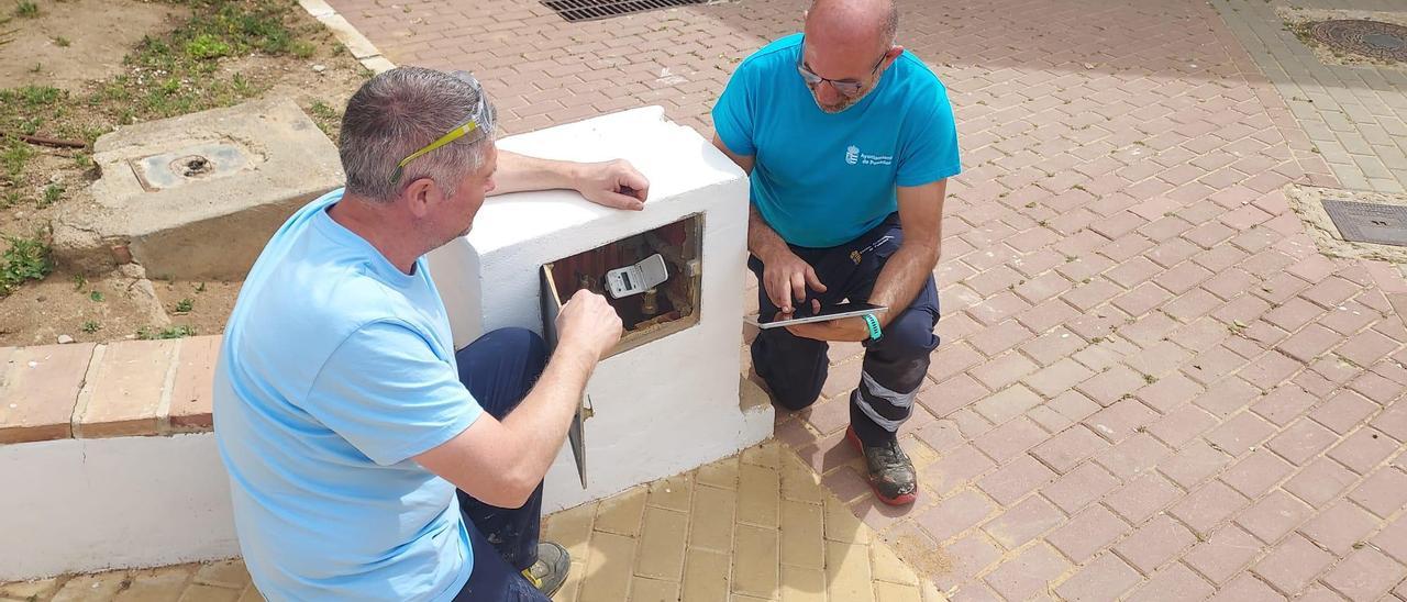 Dos técnicos revisan uno de los contadores de agua en Posadas.