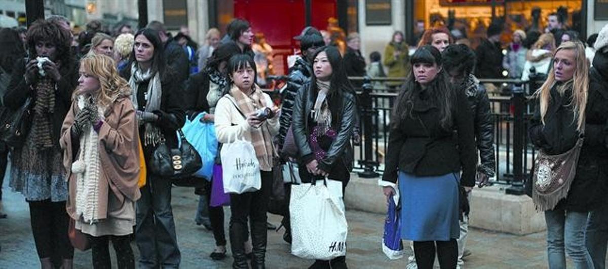 Consumisme a la baixa 8 Uns londinencs, de compres de Nadal a Oxford Street, a Londres, esperen per travessar el carrer.