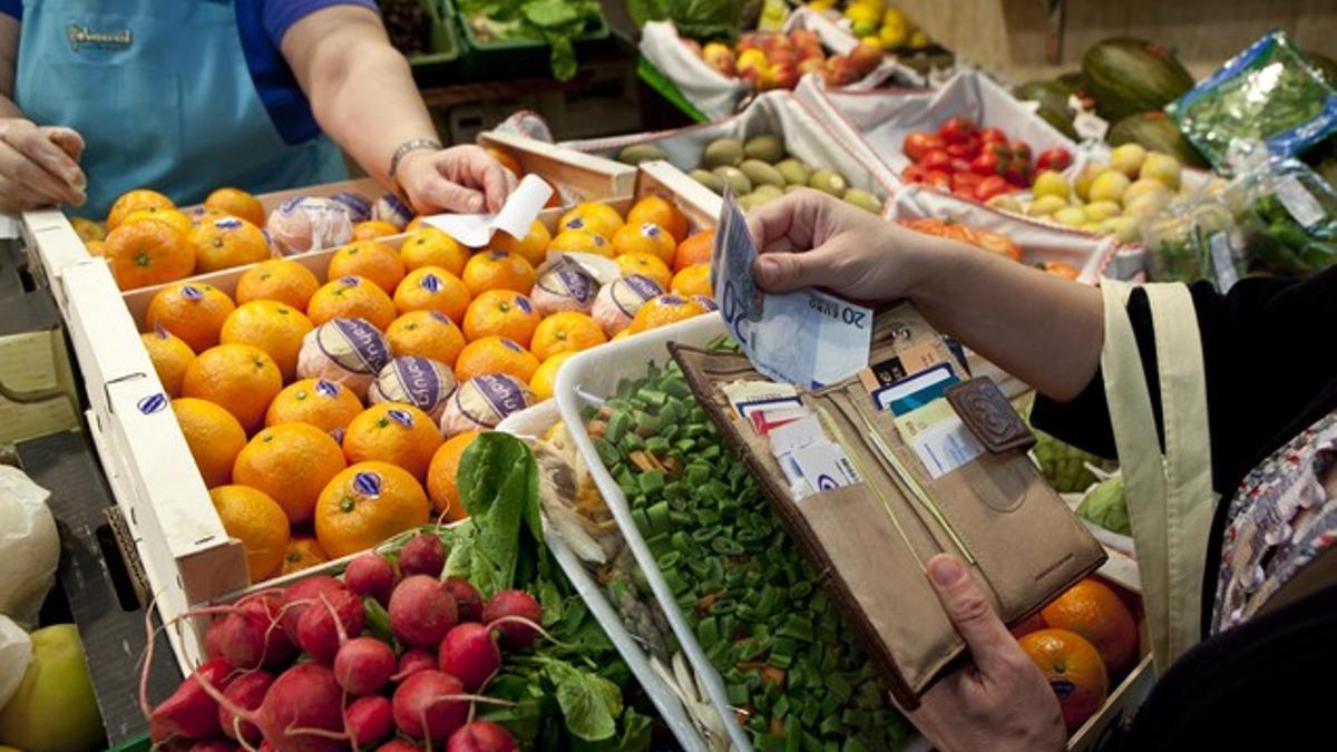 Una mujer paga la compra en el mercado de Collblanc de Barcelona.