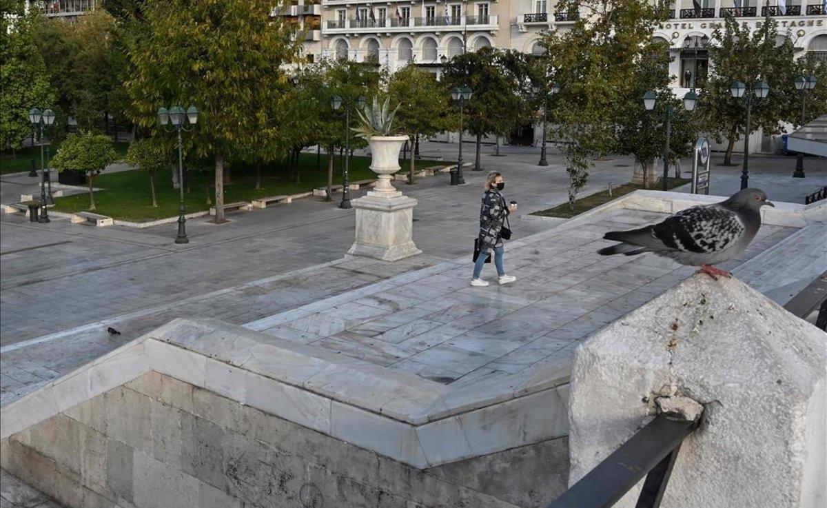 Una mujer con mascarilla pasa por la plaza de Syntagma, vacía.