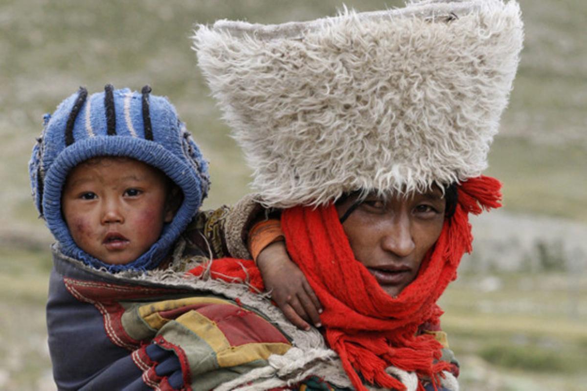 Una dona tibetana fa un pelegrinatge a la muntanya sagrada de Kailash (Tibet) amb el seu fill carregat a l’esquena.