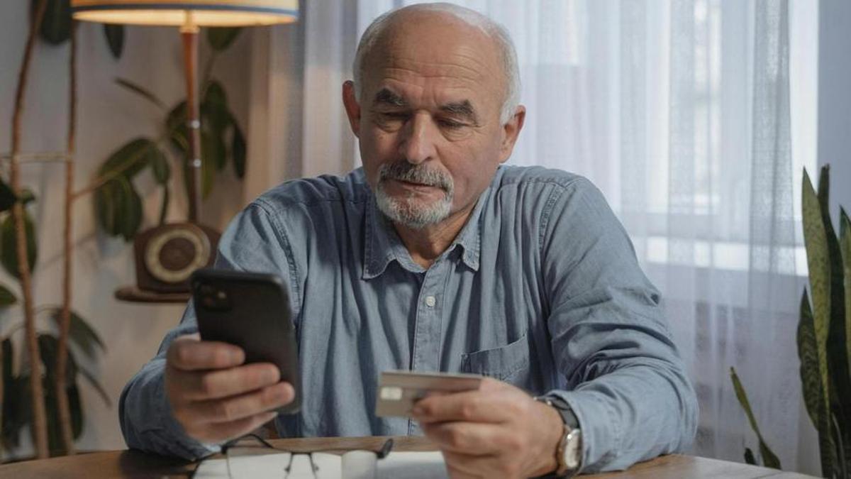 Un hombre introduce los datos de su tarjeta bancaria en el móvil.