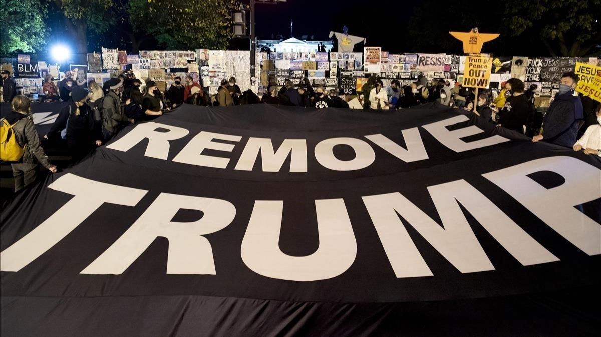 Manifestantes sostiene una pancarta que dice ’Quitar a Trump’ frente a La Casa Blanca.