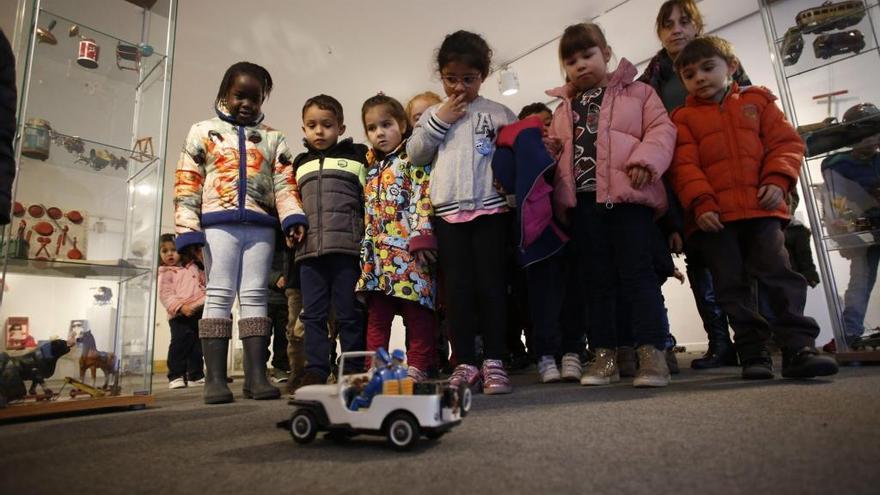 Un grupo de niños  mira un coche de juguete.