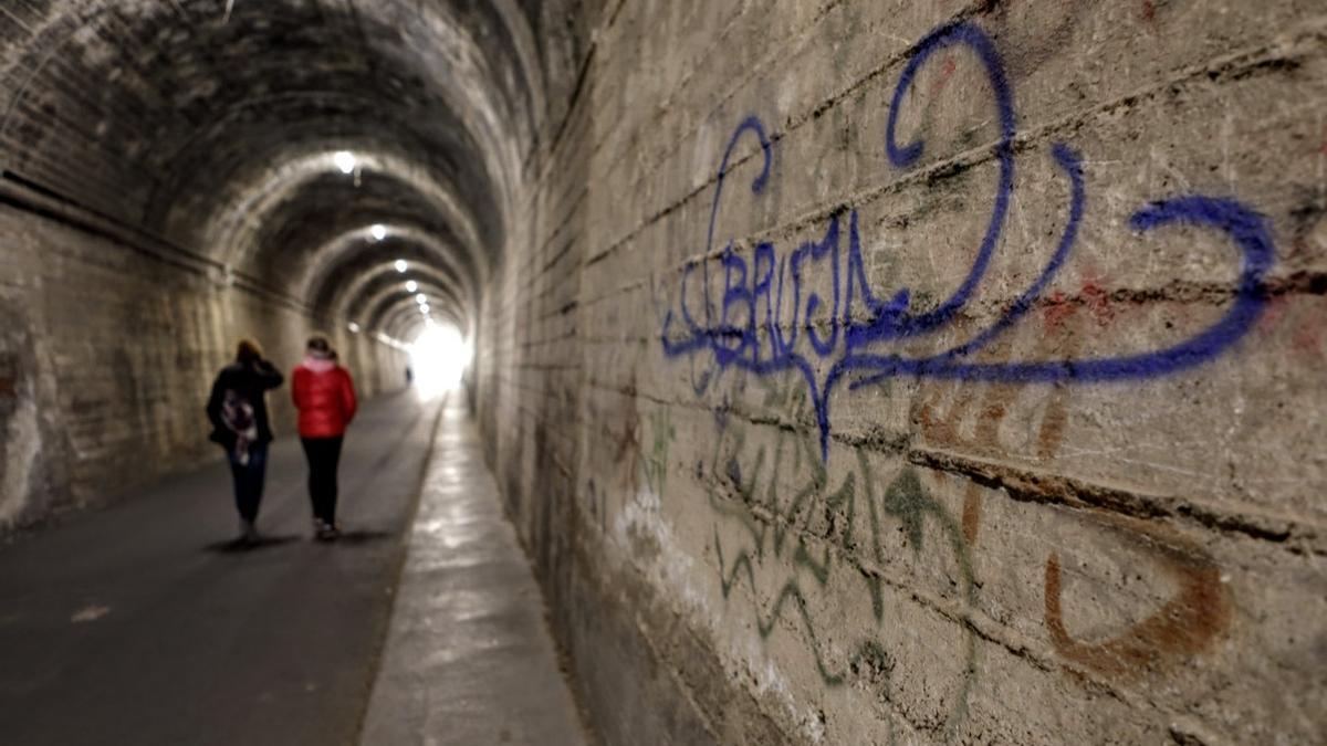 Dos personas caminando por el interior de uno de los túneles de la vía verde de Alcoy.