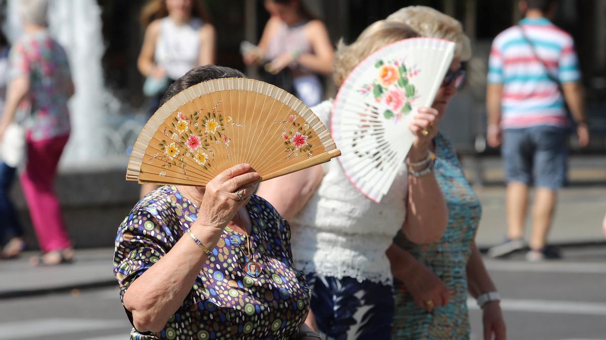 Dos mujeres se protegen como pueden de la ola de calor, este domingo.