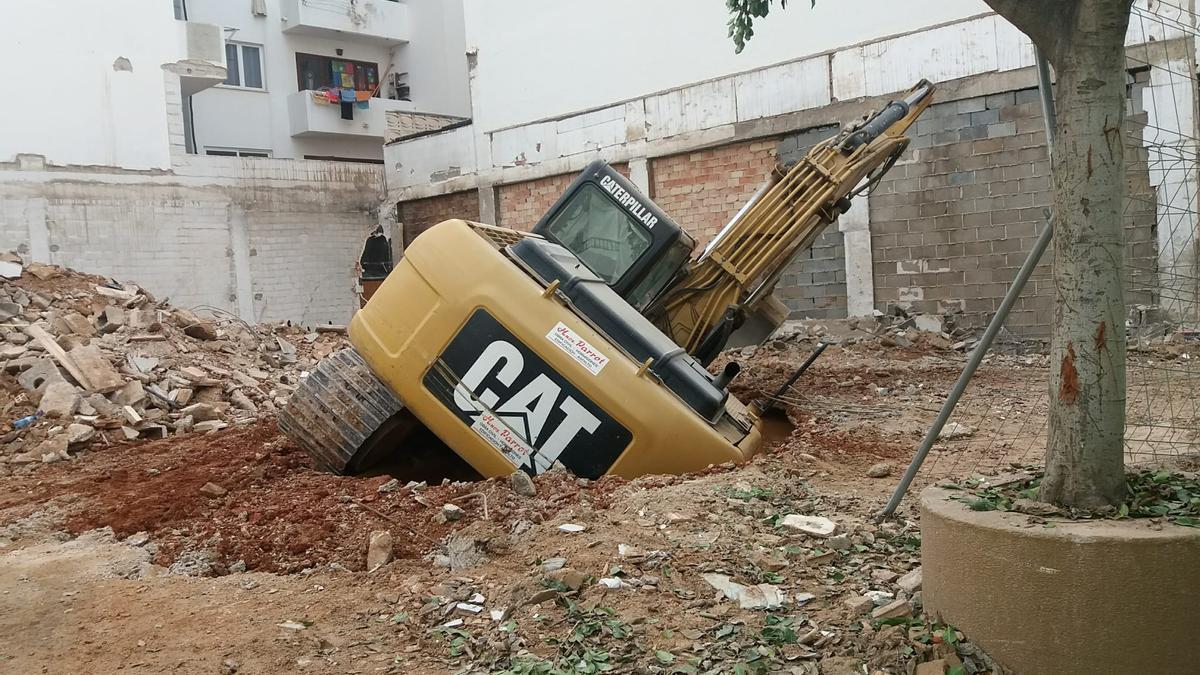 Excavadora hundida en la tierra de un solar en obras en Ibiza.