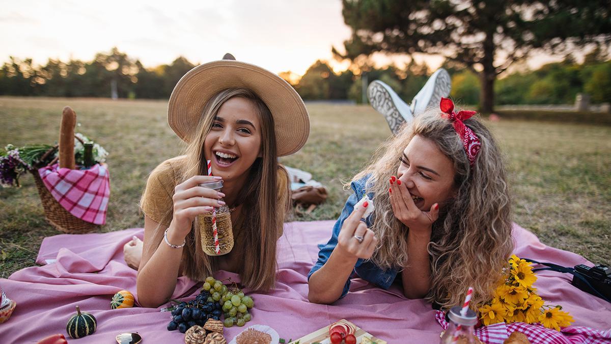 Dos chicas hacen un picnic en el campo con frutas y verduras