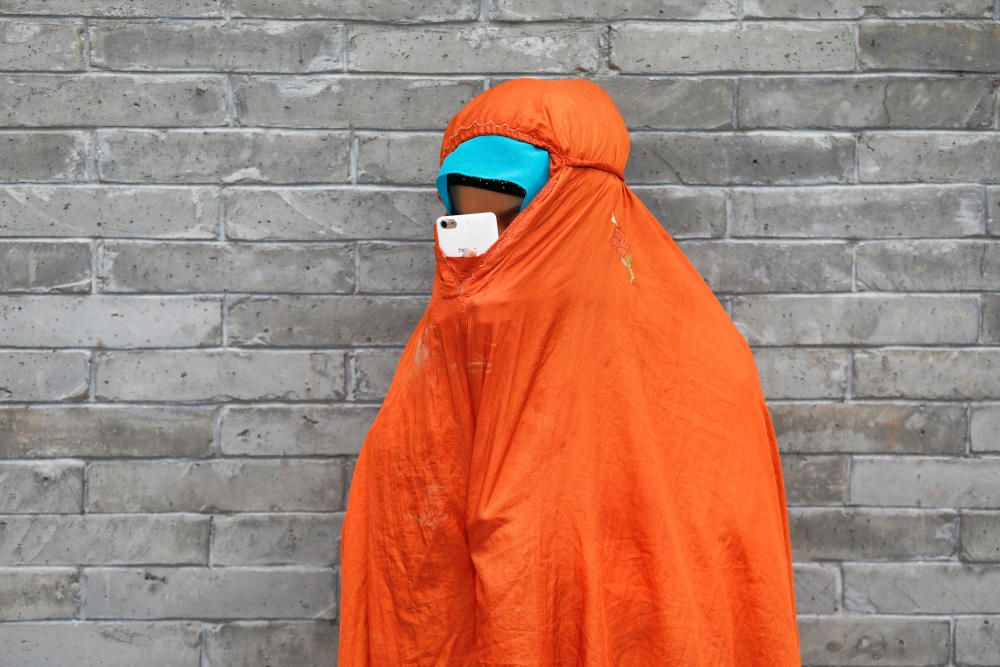 A woman uses her mobile phone under a veil on ...