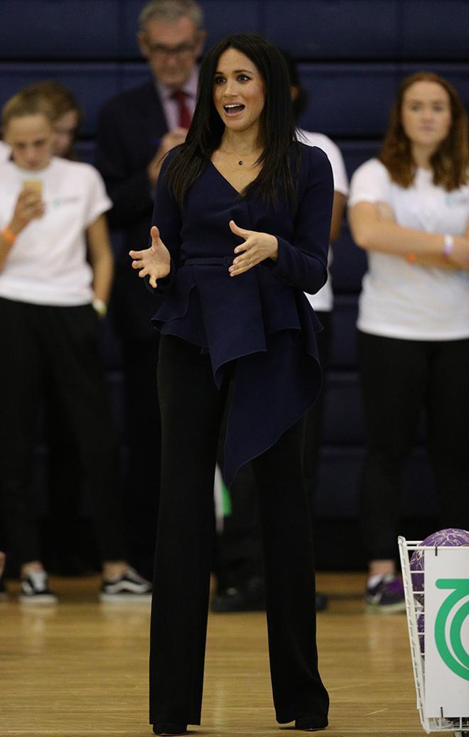 Meghan Markle en un evento con top péplum y pantalón oscuro